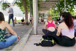 Els alumnes asseguts en el sòl escoltant la classe del professor en l'exterior de la universitat