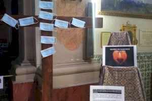 Clavan mascarillas con nombres de fallecidos por coronavirus sobre una cruz de madera en un convento de Valencia para orar por ellos