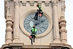 Dos escaladors reposen el parallamps i revisen el rellotge de l'Ajuntament de València